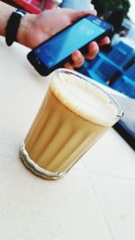 Close-up of hand holding coffee cup on table