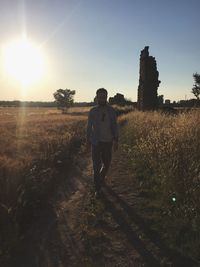 Man standing on field against sky during sunset