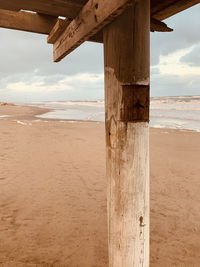 Wooden posts on beach against sky