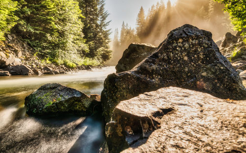 Rocks by river against sky