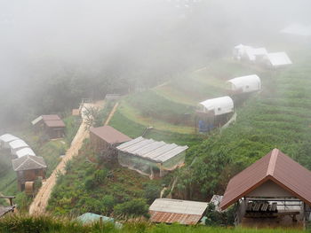 Houses on field by buildings against sky