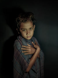 Portrait of cute girl standing against black background