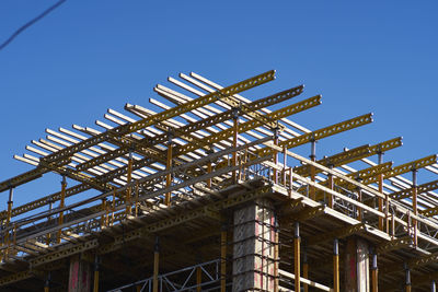 Low angle view of building under construction against clear blue sky