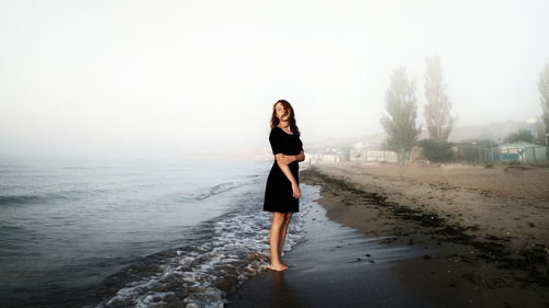 Woman standing on shore in foggy weather