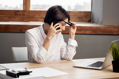 Woman using mobile phone while sitting on table