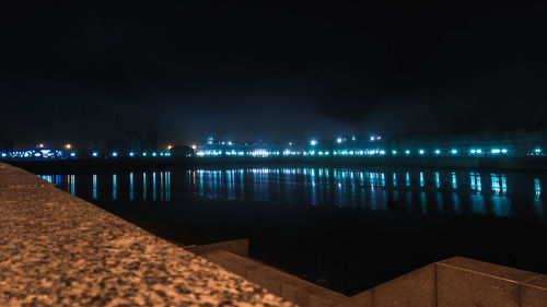 Illuminated pier over sea against sky at night