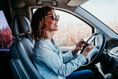 Side view of smiling woman driving car