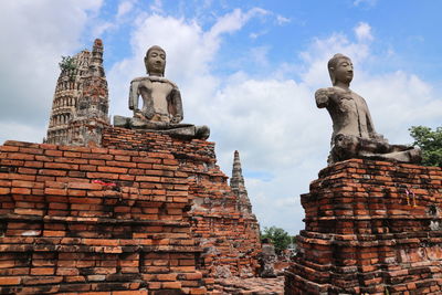 Buddha statues on old ruined wat chaiwatthanaram against sky