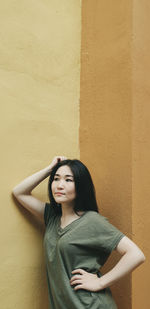 Beautiful young woman standing against wall