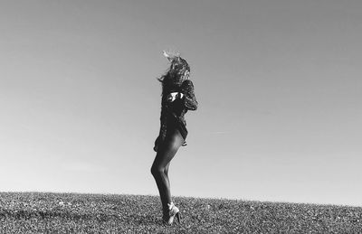 Full length of woman standing on field against clear sky