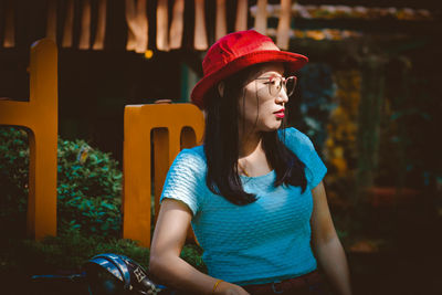 Woman wearing hat and eyeglasses standing outdoors