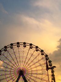 Low angle view of ferris wheel against cloudy sky