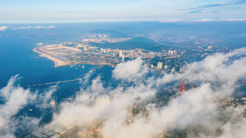 Aerial view of city by sea against sky