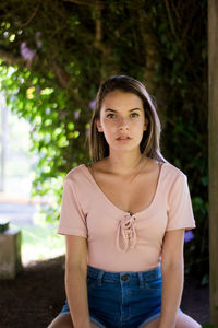 Portrait of a beautiful young woman standing against trees