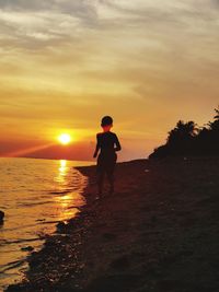 Silhouette man standing on beach against sky during sunset