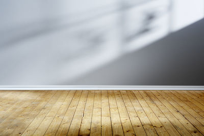 Close-up of wooden floor against wall at home