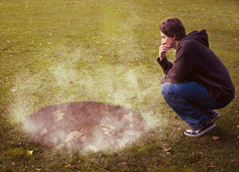 Side view of man sitting on field