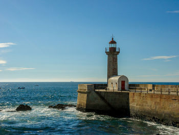 Lighthouse on beach against blue sky