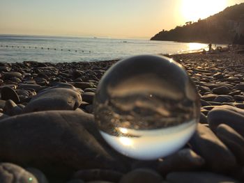 Close-up of pebbles at beach against sky during sunset