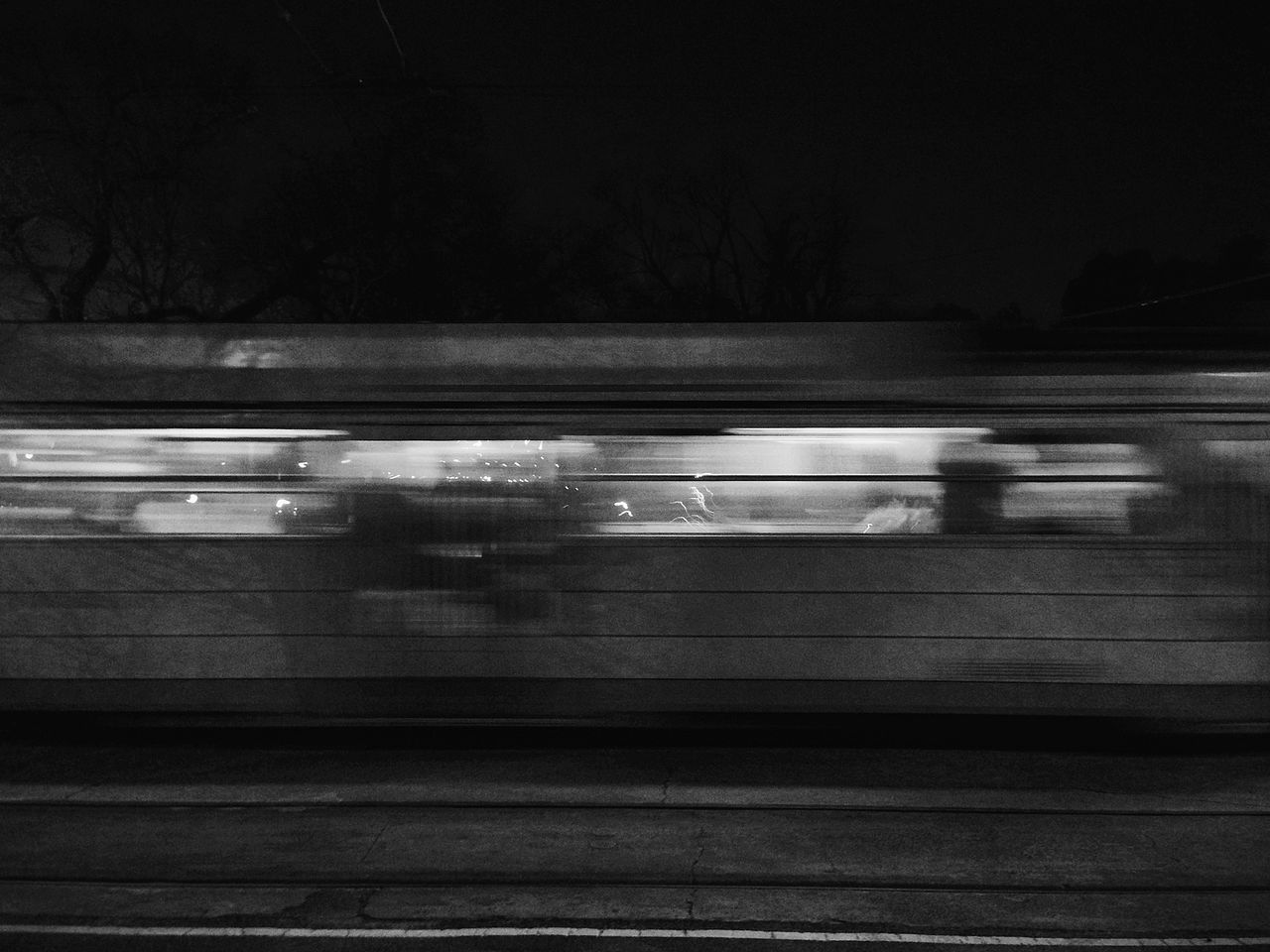 night, transportation, illuminated, railroad track, rail transportation, railroad station platform, railroad station, public transportation, mode of transport, dark, blurred motion, train - vehicle, street, motion, built structure, on the move, road, outdoors