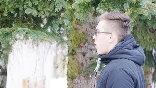 Side view of young man wearing warm clothing in park during winter