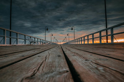 Surface level of bridge against sky at sunset