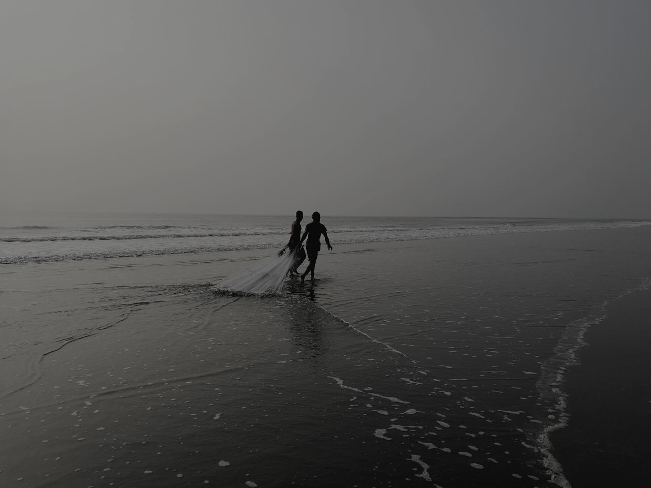 sand, beach, sea, two people, real people, nature, lifestyles, horizon over water, outdoors, shore, walking, clear sky, leisure activity, silhouette, men, scenics, beauty in nature, water, vacations, togetherness, day, sky, mammal, people, adult