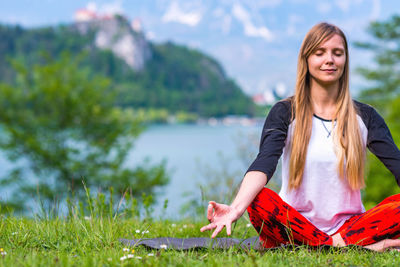 Young woman doing yoga on field