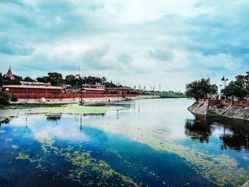 Scenic view of river by buildings against sky