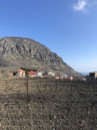 Houses on land against clear blue sky