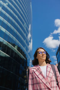 Portrait of young woman standing against sky