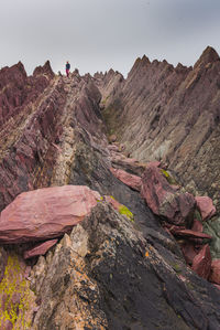 Colorful geologic rock formations on sea shore with woman and dog on far horizon