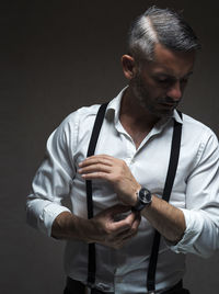 Young man looking away while standing against black background