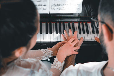 Rear view of people playing piano