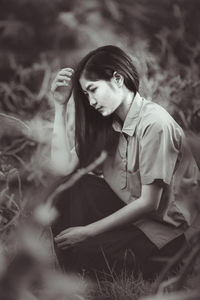 Teenager looking away while sitting on land