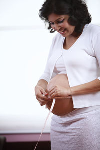 Pregnant woman measuring belly at home