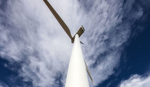 Wind turbine low angle against cloudy blue sky