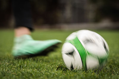 Low section of person kicking soccer ball on field