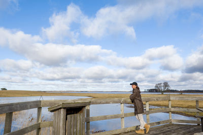 Full length of woman standing by railing against sky