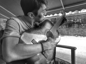 Young man playing guitar while sitting on chair