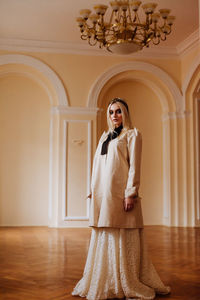 Portrait of beautiful teenage girl wearing wedding dress while standing on floor