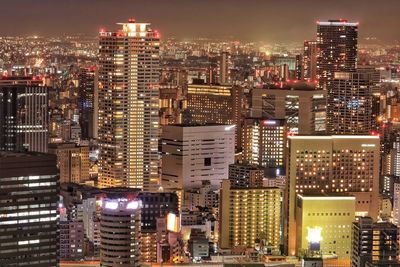 Illuminated modern buildings in city against sky at night