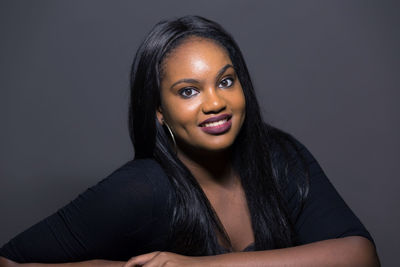 Portrait of smiling young woman against black background