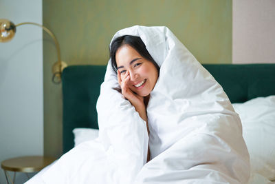 Portrait of woman lying on bed at home