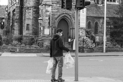 Full length of man standing on street against buildings in city