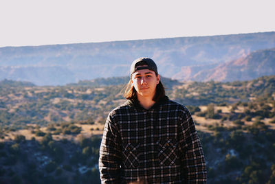 Portrait of teenage girl standing against mountains