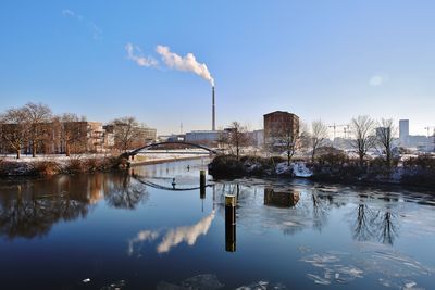 Smoke emitting from factory against sky