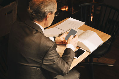 High angle view of male lawyer using smart phone while working at law office