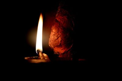 Close-up of burning candle against black background