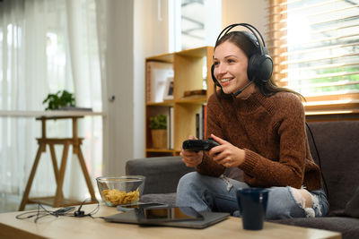 Young woman using mobile phone while sitting at home